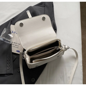 Detailed interior of a white pebbled leather bag with magnetic snaps and compartments