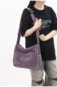 Detail of purple washed canvas messenger bag featuring multi-pocket design and adjustable strap