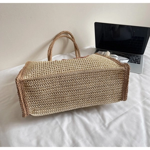 Detailed macro view of the sturdy woven base and textured finish of the straw handbag