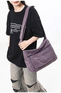 Close-up of a purple washed canvas messenger bag featuring a front pocket and wide strap