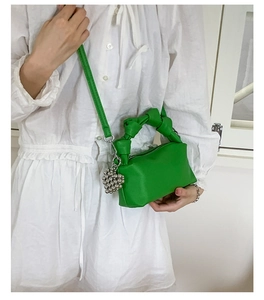 Detail of green pleated tote bag with knot handle and silver heart bead charm