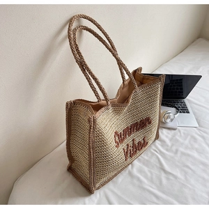 Detail of the Summer Vibes embroidery on a woven straw tote bag with long shoulder straps