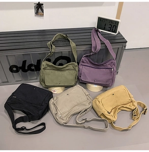 Detailed view of large capacity washed canvas messenger bags in five different colors