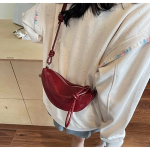 Detail of dark red crescent bag with soft leather texture and adjustable knotted strap