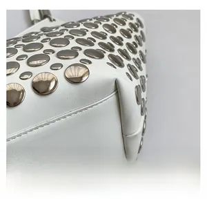 Vue macro détaillée des rivets métalliques argentés sur le sac à bandoulière en cuir blanc