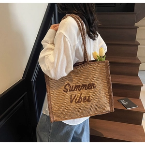 Detail of Summer Vibes embroidery on a natural woven straw shoulder bag for beach trips