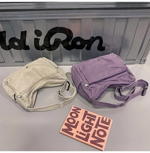 Detail view of khaki and purple canvas messenger bags with adjustable straps on metal chest