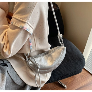 Detail of silver crescent moon bag with metallic texture and minimalist knotted strap