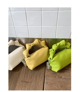 Detailed shot of knotted handbags in beige, yellow, and green with lychee texture