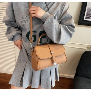 Detailed view of the textured brown lychee leather finish and adjustable shoulder strap