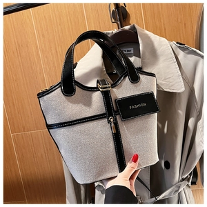Dettaglio della borsa a secchiello in tela beige con finiture in pelle nera