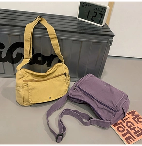 Detail of canvas messenger bag with multiple pockets and adjustable strap in yellow and purple