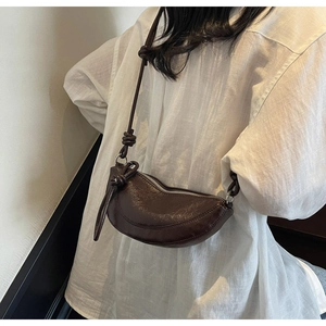 Detail of dark brown crescent bag with knotted strap and oil wax leather texture