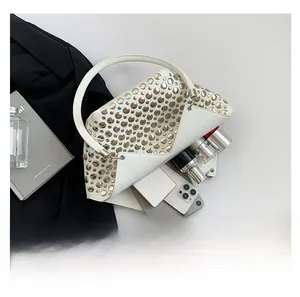 Détail du sac à main beige clouté montrant la capacité intérieure pour les accessoires