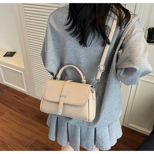 Detailed macro of the beige pebble leather texture and metallic buckle on the handbag
