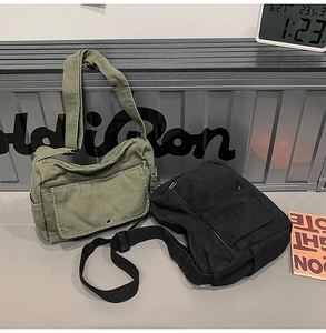 Detail view of khaki and black canvas messenger bags with adjustable straps and multi-pockets