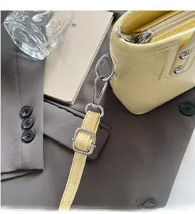 Κοντινή λήψη της γυαλιστερής τσάντας bucket με ασημένια στοιχεία σε γκρι σακάκι