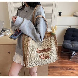 Detail of Summer Vibes straw tote bag with rope handles held by a model in a warm setting