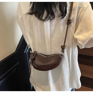 Detail view of dark coffee crescent bag with knot strap and silver zipper closure