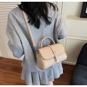 Close-up of beige crossbody bag with lychee texture leather and silver metal buckle