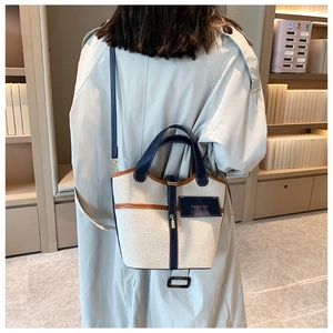 Vista dettagliata della borsa a secchiello in tela con dettagli in pelle su modella