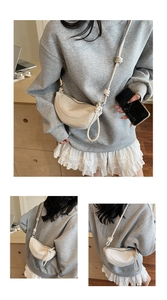 Detail of cream crescent bag featuring knotted strap and contrast stitching on soft leather