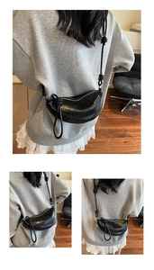 Detail of black crescent hobo bag with knotted shoulder strap and glossy pleated leather