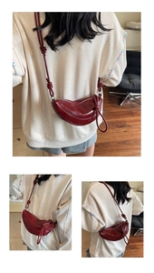 Detail showing deep burgundy crescent leather bag with unique knotted shoulder strap