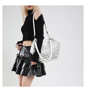Sac fourre-tout en cuir blanc avec rivets métalliques argentés porté par un mannequin