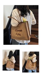 Detail of woven straw tote bag with Summer Vibes embroidery and slim shoulder handles