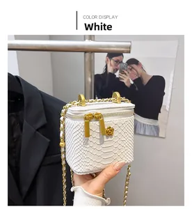 Detailed view of white snake-textured mini bag with gold chain and floral pendant