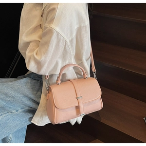 Detailed view of pink pebble grain leather shoulder bag worn by model on stairs