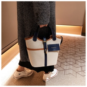 Dettaglio borsa a secchiello in tela beige con finiture in pelle e logo Fashion