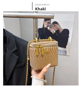 Close-up of khaki mini square bag with crocodile pattern and gold flower buckle