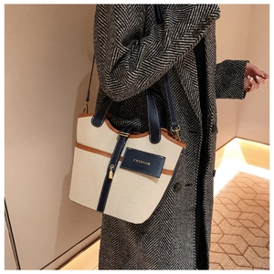 Dettaglio della borsa a secchiello in tela retrò con finiture in pelle blu navy