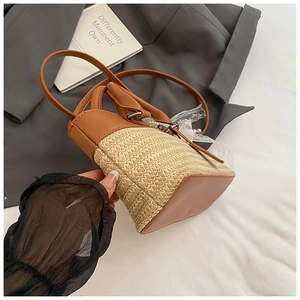 Close-up of straw woven tote with brown leather handles and pearl lace bow detail