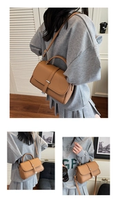 Detail of caramel brown litchi pattern leather bag with metal buckle and top handle
