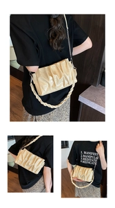 Detail of beige pleated cloud bag with silver chain and braided strap on female model