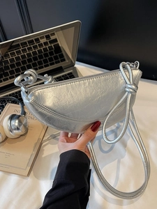 Silver metallic crescent moon hobo bag with knotted shoulder strap and zipper closure