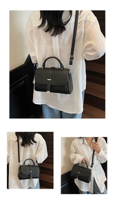 Detail view of black lychee grain leather handbag with silver buckles and top handle