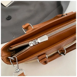 Detailed macro view of the silver metal zipper and brown leather texture on a tote bag