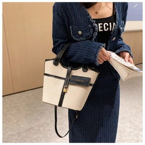 Dettaglio borsa a secchiello in tela con finiture in pelle nera e lucchetto su tweed