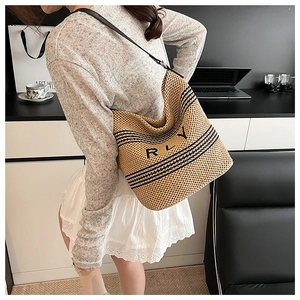 Detail of a woven bucket bag with RLY pattern and long strap on a casual model