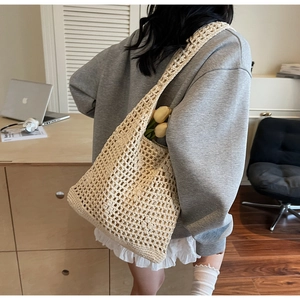 Detailed view of beige handmade crochet bucket bag with hollow mesh texture and wide strap