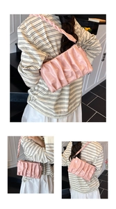 Detail of pink pleated cloud bag featuring woven shoulder strap and glossy PU finish