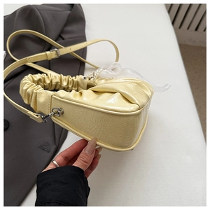 Détail du sac jaune pâle avec poignée en perles et nœud décoratif en résille blanche