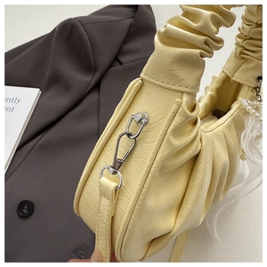 Détail du sac à main plissé jaune clair avec chaîne en perles et breloque en soie