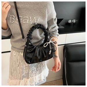 Détail du sac croissant noir plissé brillant avec breloque nœud en perles et sangle