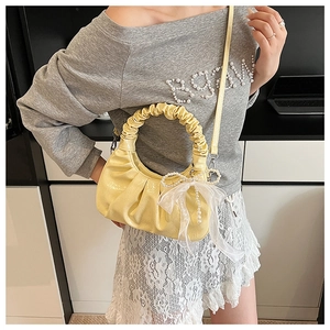 Détail du sac nuage plissé jaune avec nœud en dentelle blanche et breloque perle