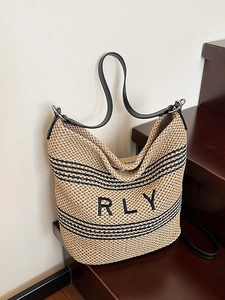 Summer straw shoulder bag with black stripes and RLY embroidery on wooden stairs